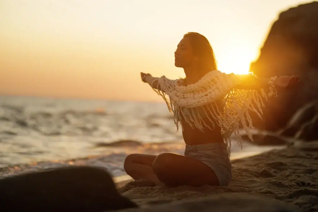 mujer relajada en la playa en el atardecer para reducir el estrés y la ansiedad