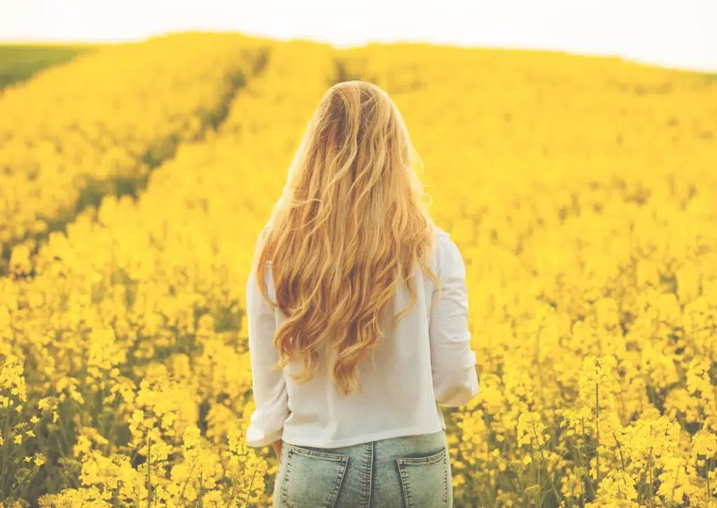 Mujer en el campo con el pelo largo que usa un acondicionador revitalizante con hidratación profunda para el cabello