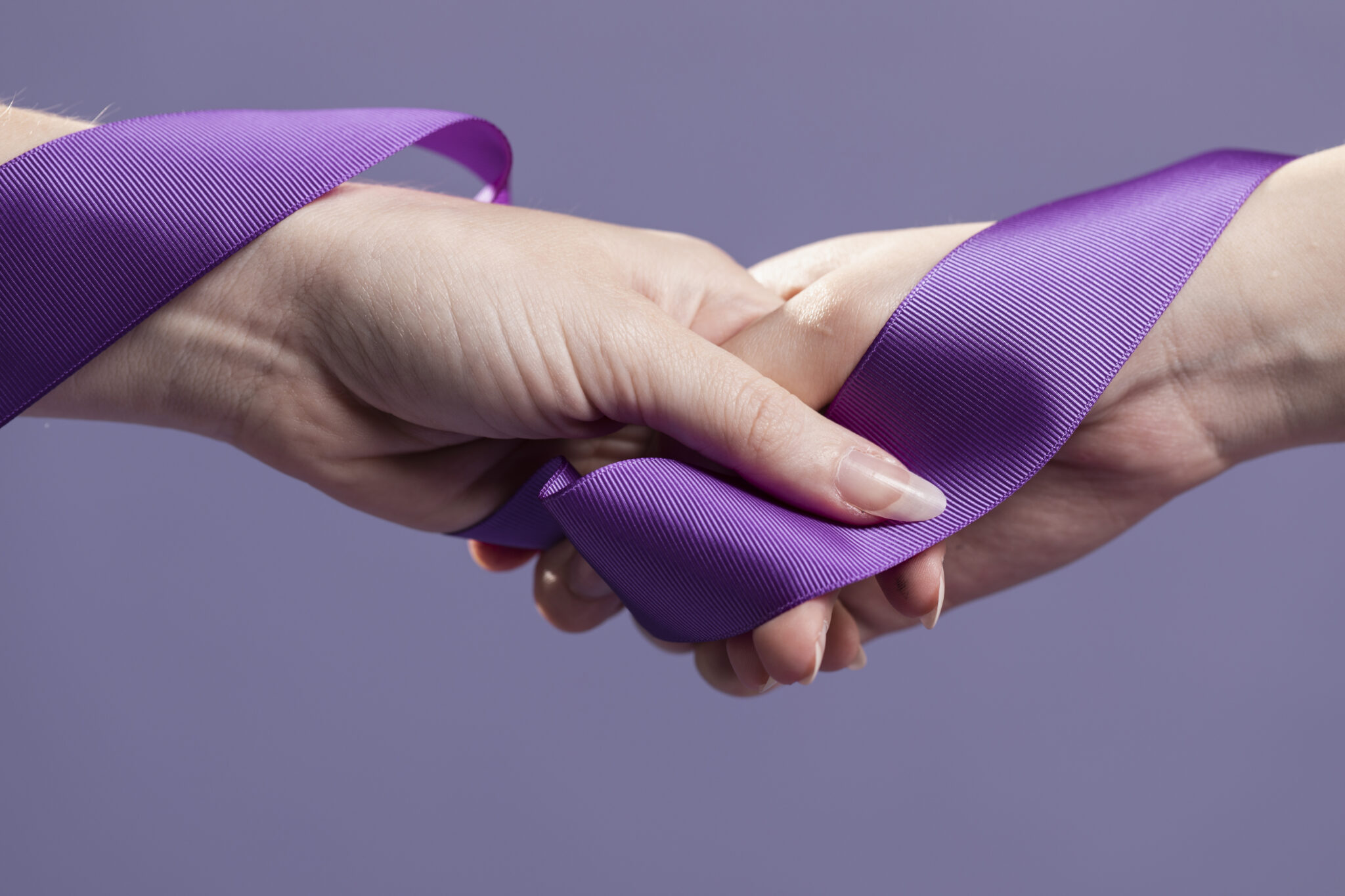 Manos con un lazo morado entrelazado, el color que se identifica con la concienciación sobre el LUPUS
