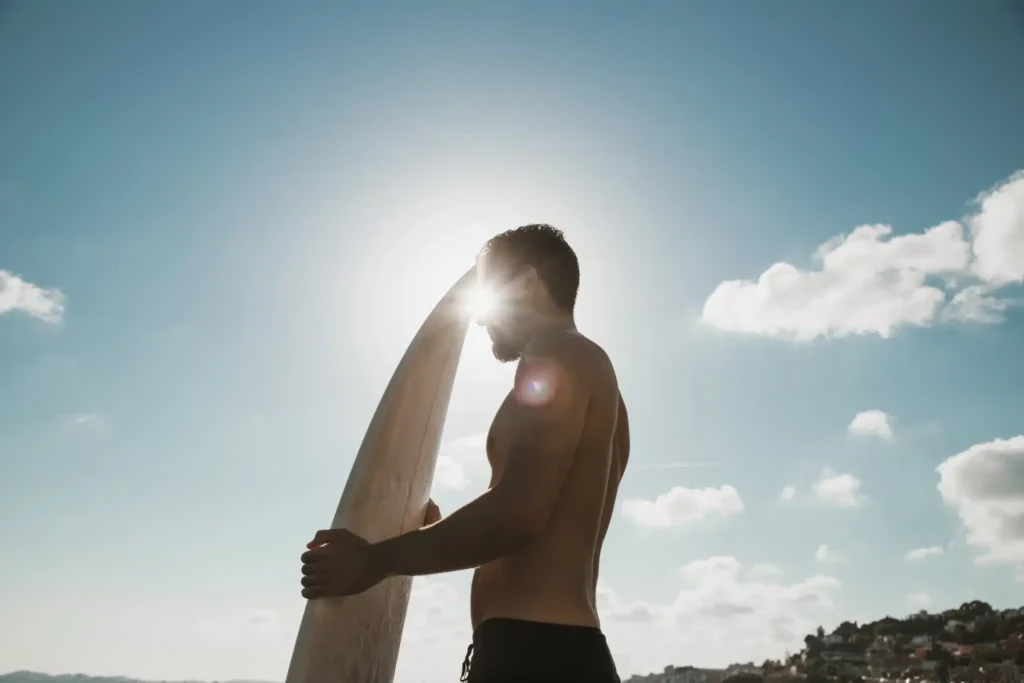 hombre con tabla de surf que simboliza la importancia de la actividad física para una mejor calidad de vida