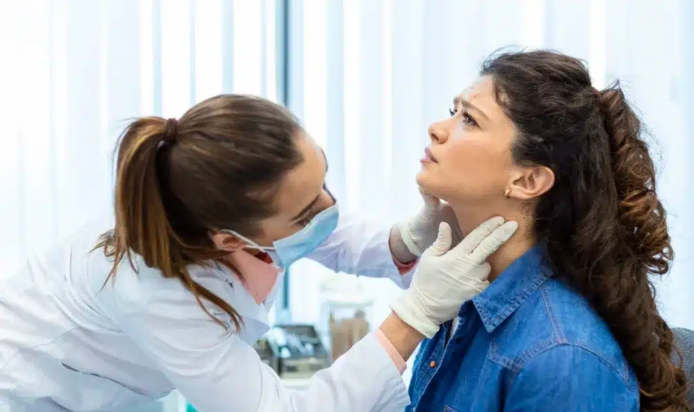 Médico inspeccionando la glándula tiroides de un paciente