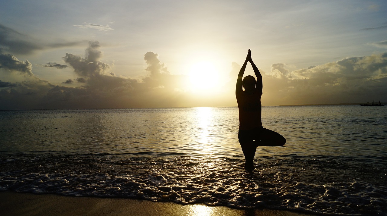 Persona haciendo una postura de Yoga al atardecer para cuidar su bienestar