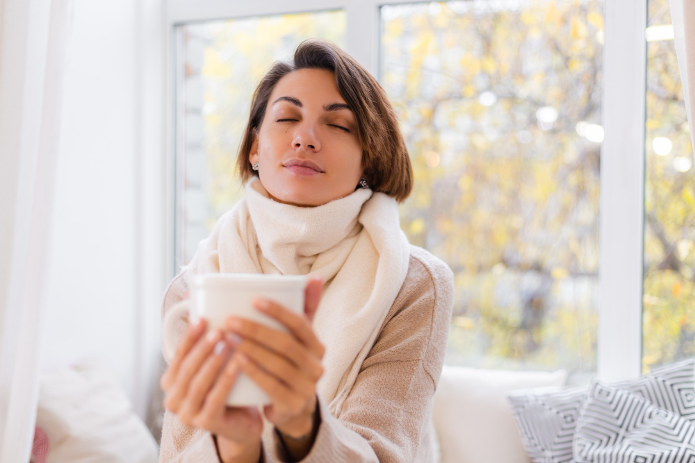 Mujer tomando una infusión caliente para calmar los síntomas de un resfriado.