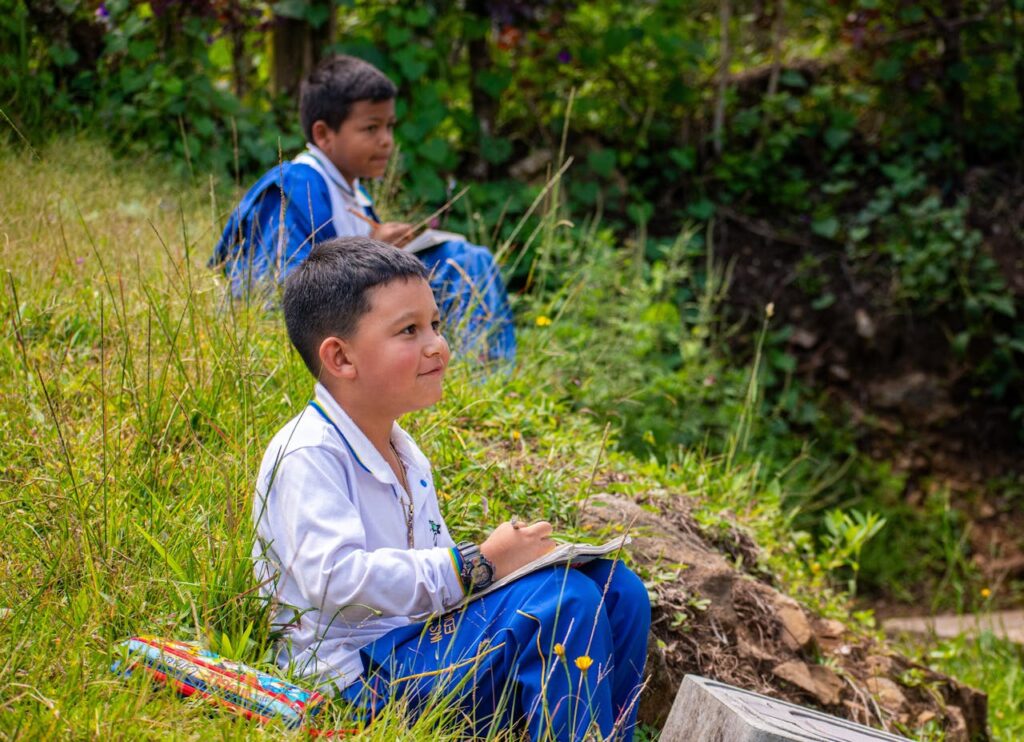 Niños sentado en una pradera. Mejorando el rendimiento escolar con menos estrés estudiantil.