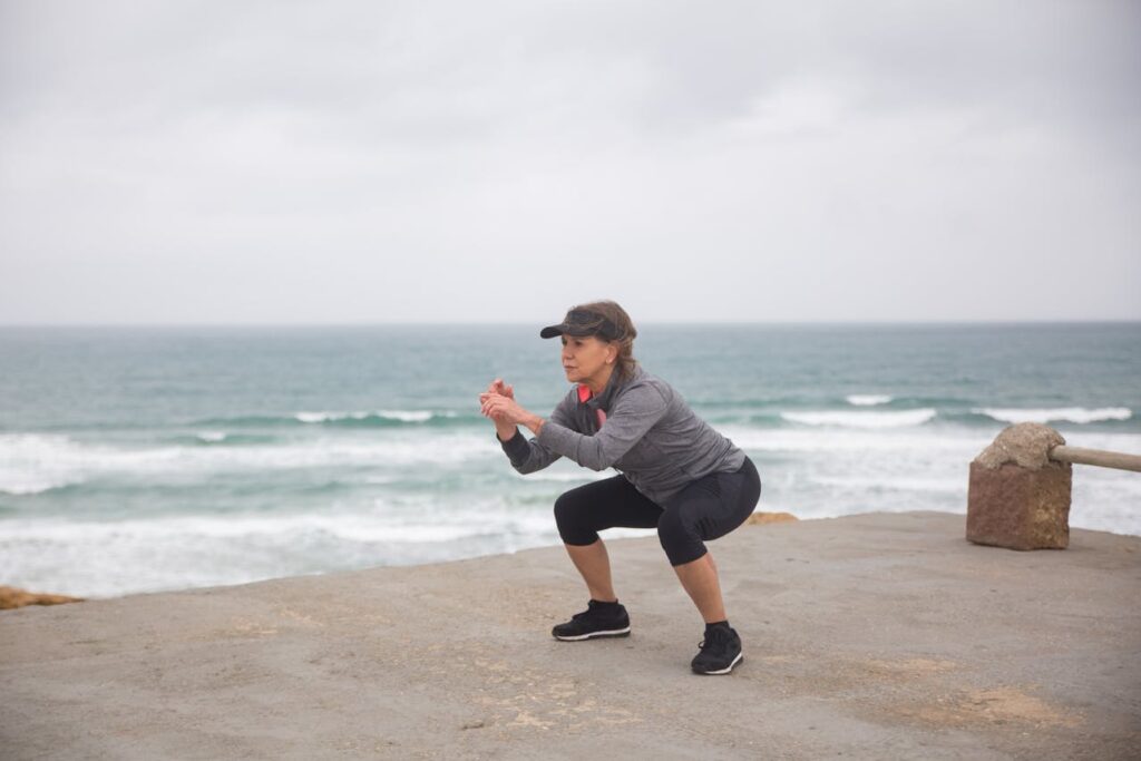 Mujer mayor haciendo ejercicio frente al mar como parte de su rutina de autocuidado personal